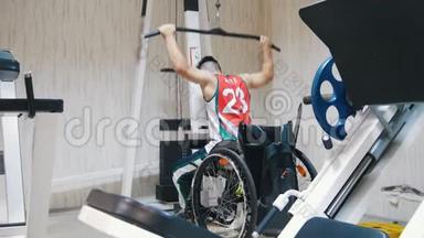 一名残疾人坐在轮椅上在健身房举重的侧视图